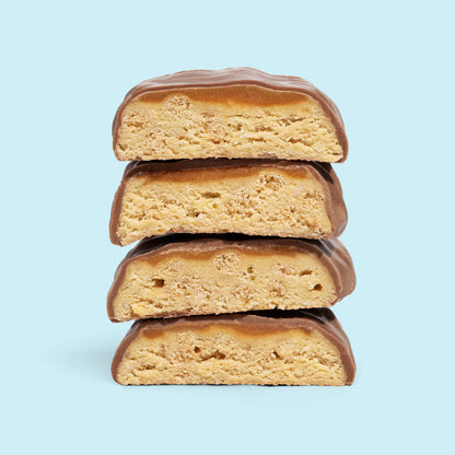 Stack of Coconut Crunch meal replacement bars coated in milk chocolate on a light blue background.